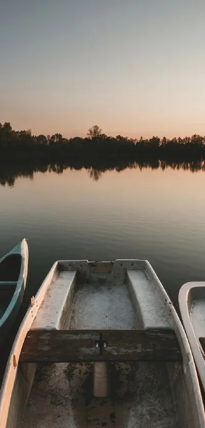 Tranquil sunset over lake with boats reflecting on calm water.