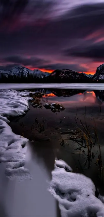 Serene sunset reflecting over icy lake with snow-capped mountains.