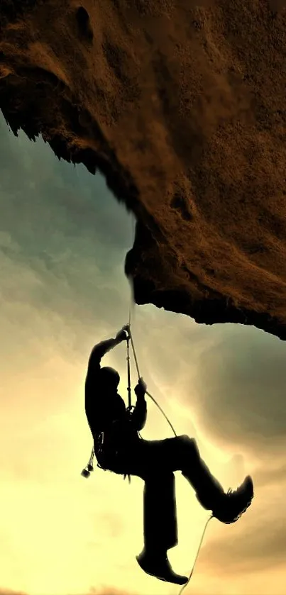 Silhouette of rock climber against sunset sky in brown hues.