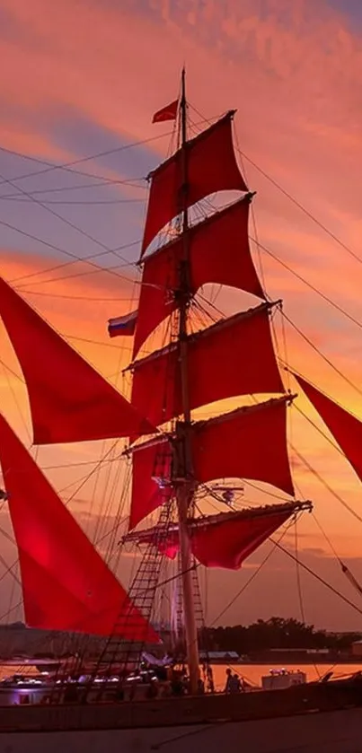 Sunset sailboat with red sails on calm ocean.