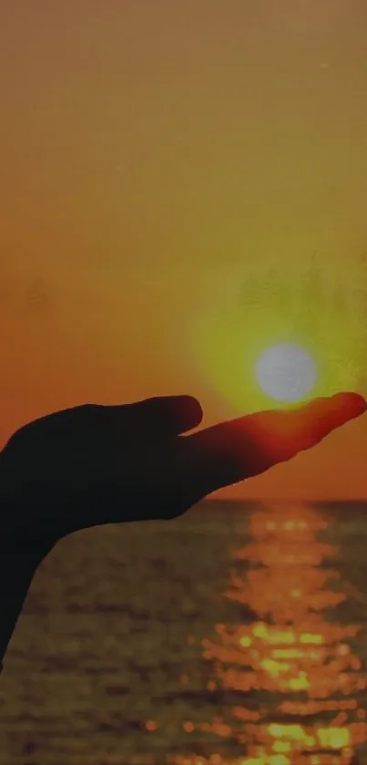 Hand silhouetted against a sunset over the ocean, with golden hues.