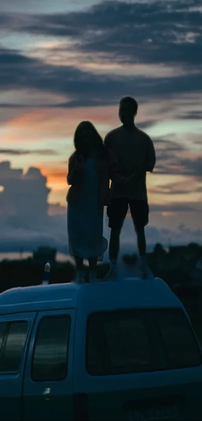 Couple silhouetted on vintage van against sunset sky.