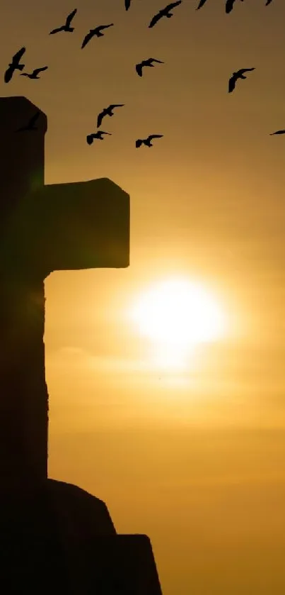 Sunset silhouette of cross with birds flying in sky.