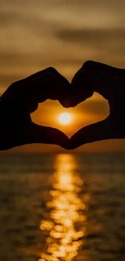 Silhouette of hands forming a heart at sunset over the ocean.