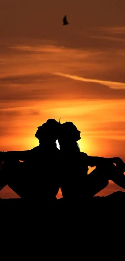 Silhouette of two people at sunset with vibrant orange sky and birds flying.