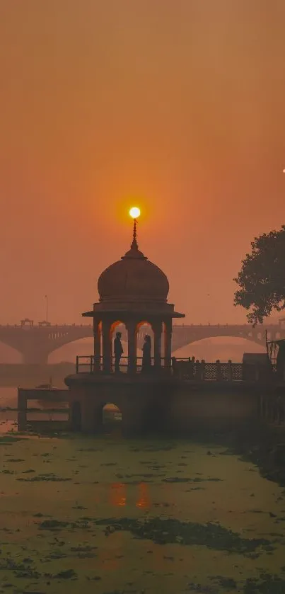 Silhouette structure against a vibrant sunset over a river.