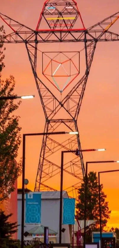 Geometric structure against orange sunset sky with silhouetted trees.