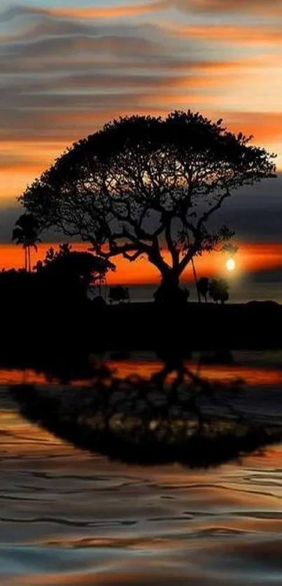 Silhouette of a tree at sunset with reflection on water.