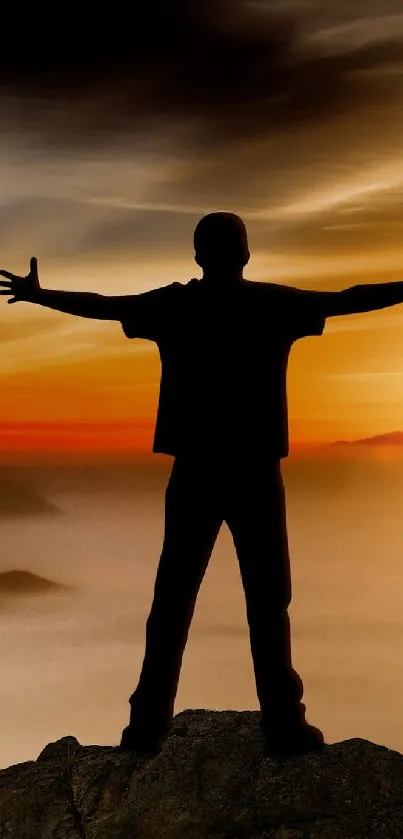 Silhouette of person embracing sunset on a misty mountain.