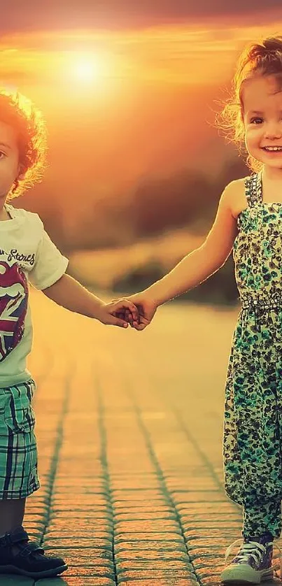 Two kids smiling and holding hands at sunset with a glowing sky.