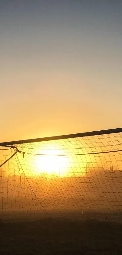 Soccer goal backlit by sunset with orange sky.