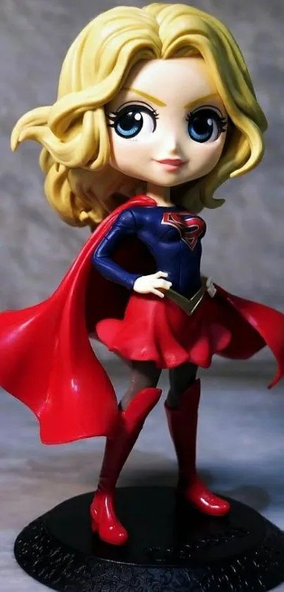 Chibi superhero figurine with red cape on a phone wallpaper.