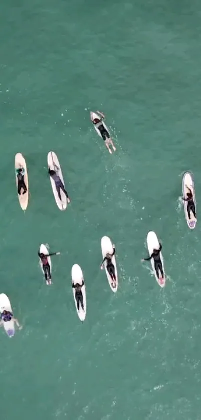 Aerial view of surfers in the teal ocean.