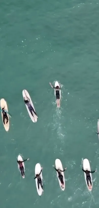 Aerial view of surfers on aqua green ocean waves.