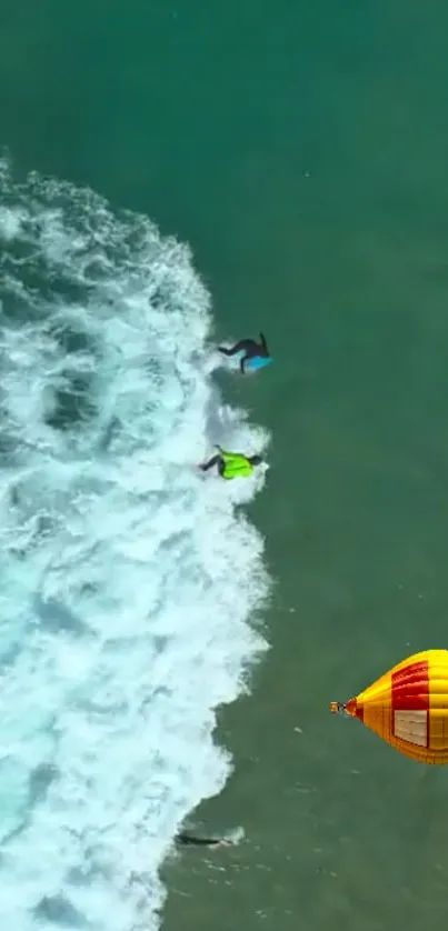 Aerial view of surfers and a hot air balloon over turquoise ocean waves.