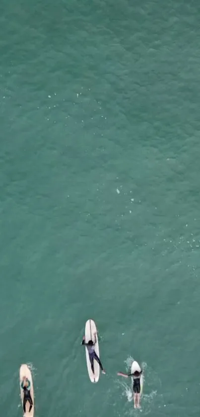 Aerial view of turquoise waters with surfers paddling.