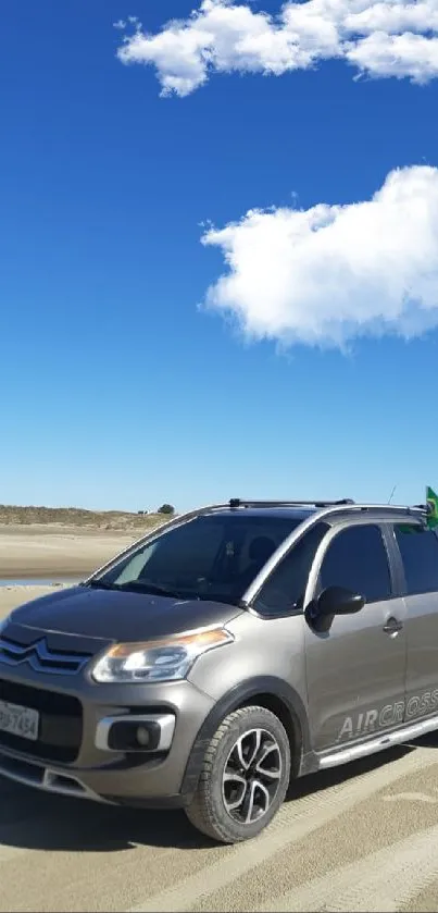 SUV driving on a sunny beach under clear blue skies.