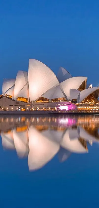 Sydney Opera House reflecting in quiet waters at dusk with a clear blue sky.