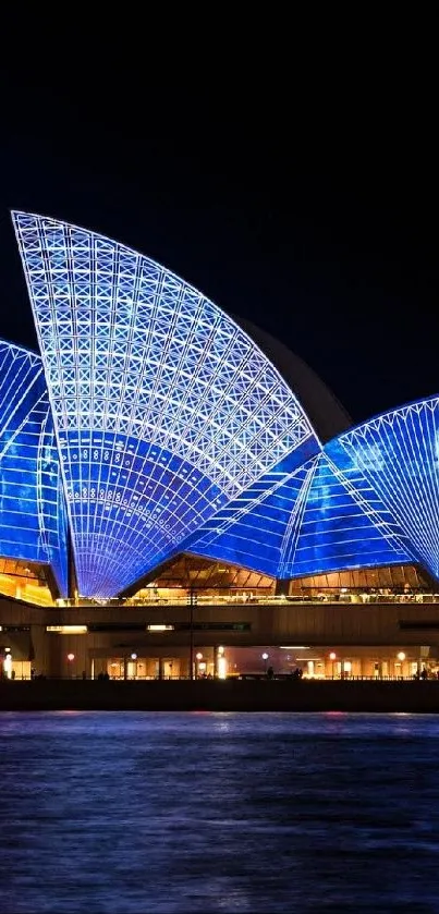 The Sydney Opera House illuminated at night, reflecting vibrant blue lights.