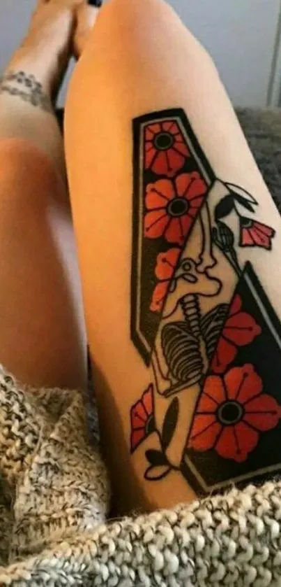 Intricate tattoo art on a leg, showcasing red flowers and geometric shapes.