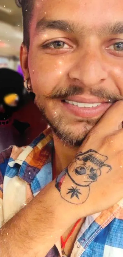 Smiling man with tattoo and colorful shirt.