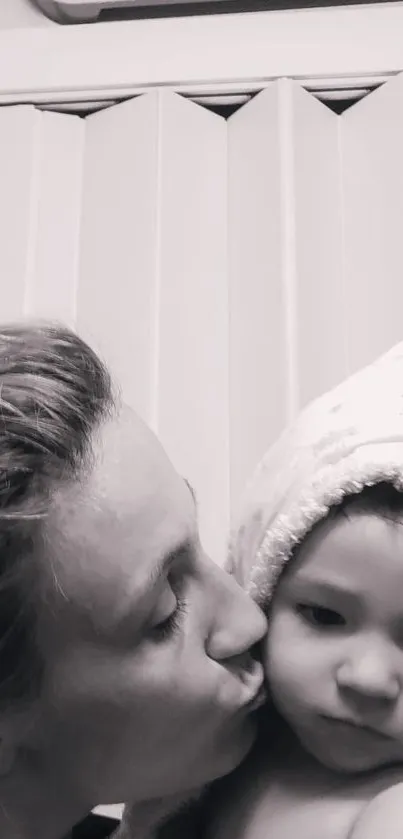 Black and white image of mother kissing baby lovingly.