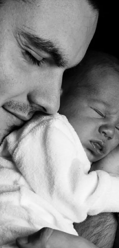 Black and white photo of a father lovingly holding his sleeping baby.