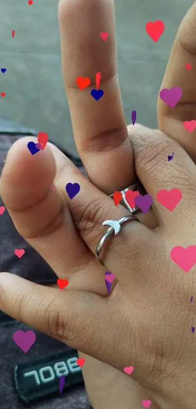 Close-up of intertwined hands with rings in a casual setting.