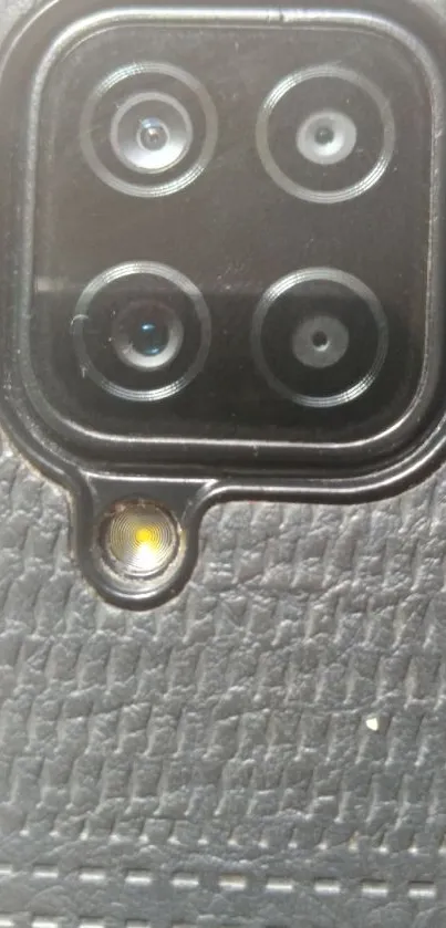 Close-up of a phone camera with textured black background.