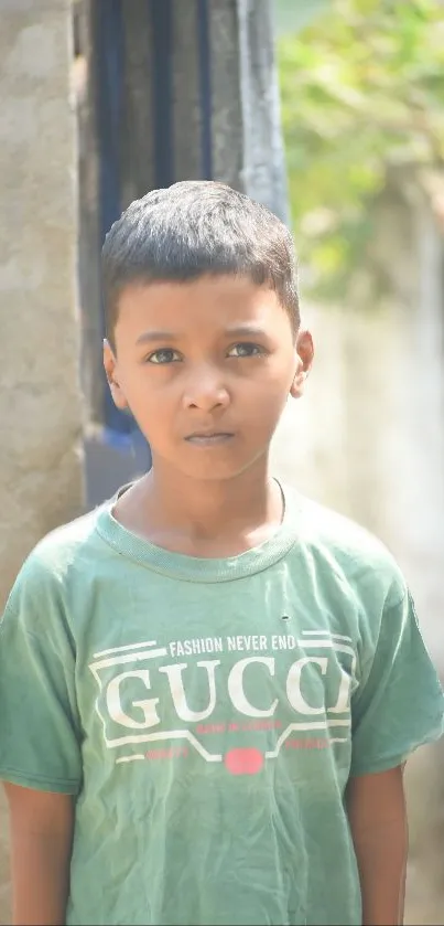 Young boy in green shirt stands in sunlight, looking thoughtful.