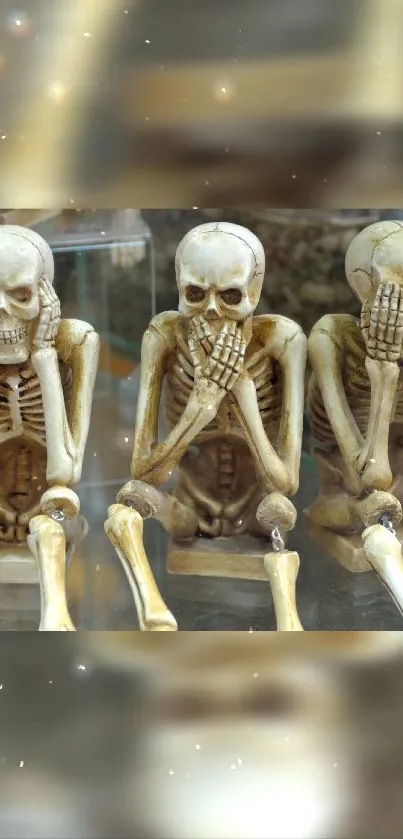 Three wise skeletons in see, hear, speak no evil pose on mobile wallpaper.