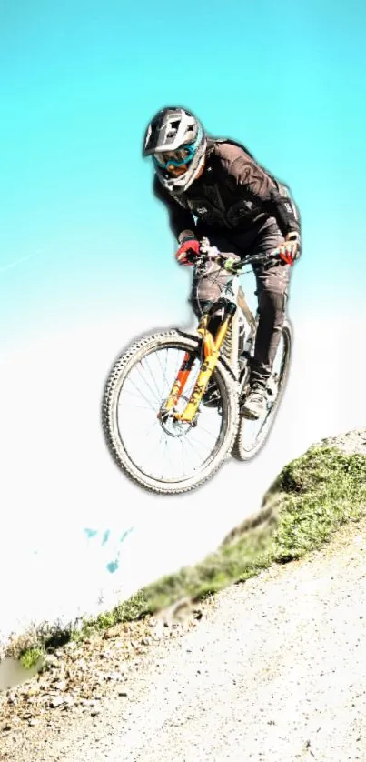 Biker jumps over hill on mountain bike under clear blue sky.