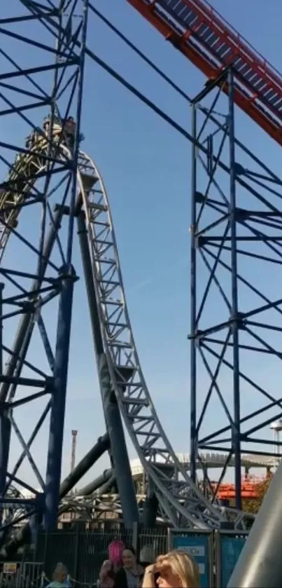 Roller coaster with blue sky and tall steel loops in the background.