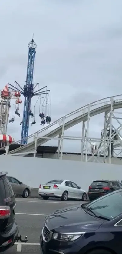 Exciting theme park ride with a roller coaster and swings against a cloudy sky.