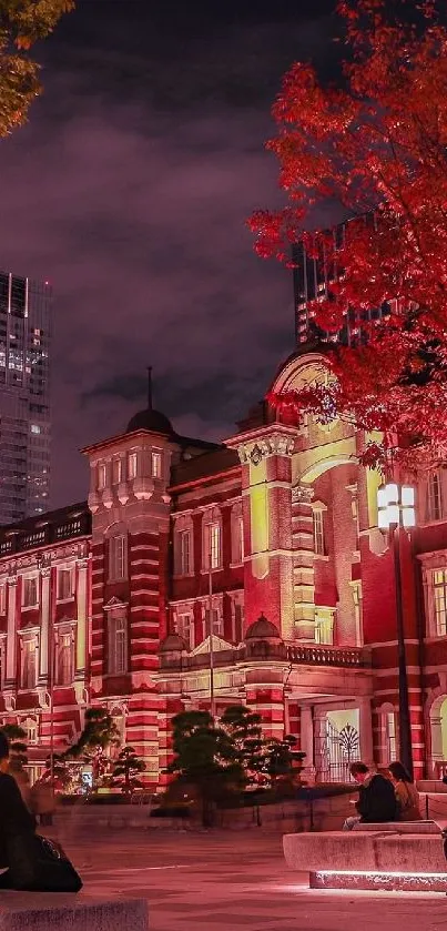 Tokyo Station at night with red lights and a crimson tree in autumn.