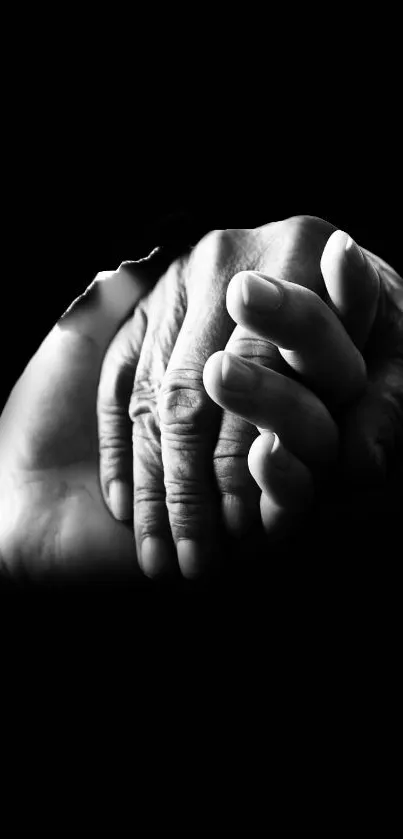 Black and white hands showing compassion on dark background.