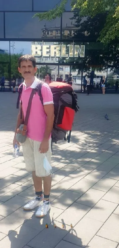 Tourist in Berlin with urban backdrop and greenery.