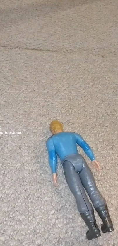 Toy action figure on textured carpet wallpaper.