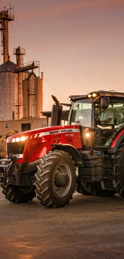 Tractor on a farm at sunset with silos in the background.