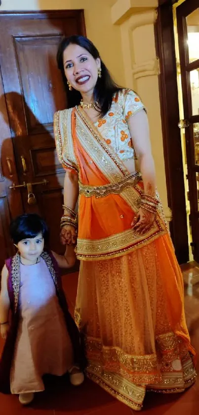 Mother and child in traditional Indian attire with vibrant orange dress.