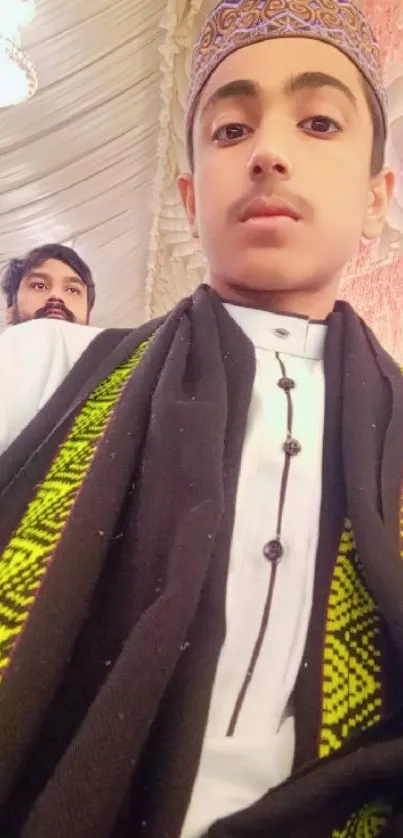 Young boy in traditional attire with decorative background.