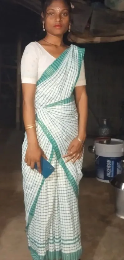 Woman in traditional sari posing indoors with metal pots.