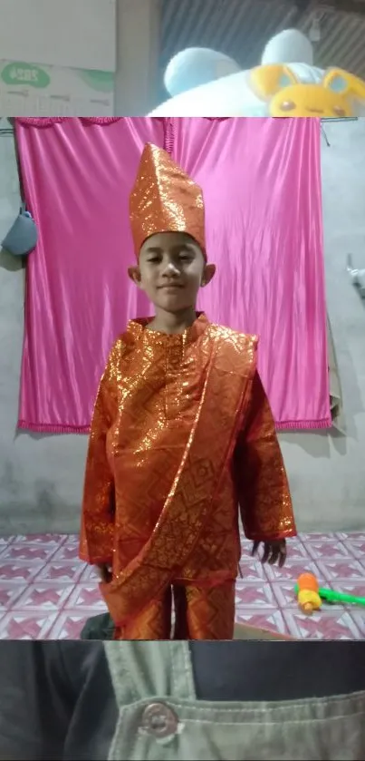 Boy in traditional attire with vibrant pink background.