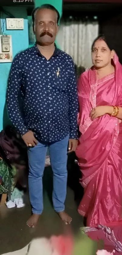 A couple in traditional Indian attire in a home setting.