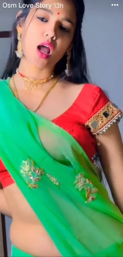 Woman in vibrant traditional attire with green saree and red blouse.