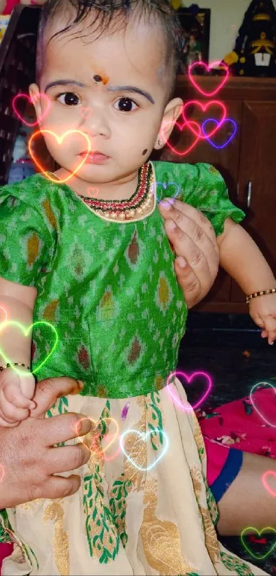 Baby in vibrant green traditional attire.