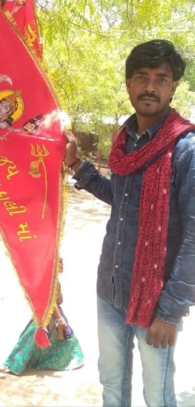 Man holding a bright festival flag outdoors.