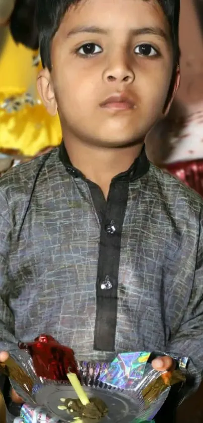 Child in traditional festive attire holding a decorative platter.