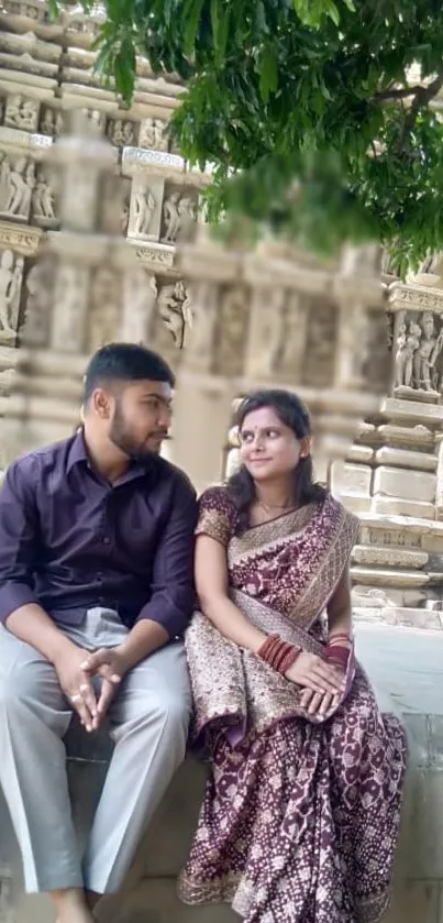 Couple in traditional attire at ancient temple with green foliage.