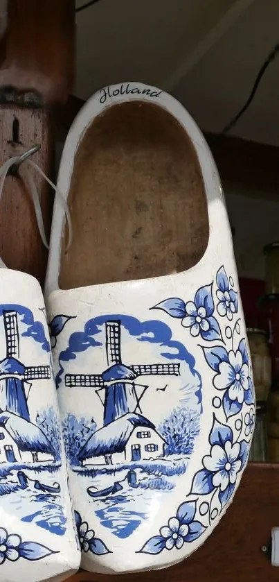 Traditional Dutch clogs with blue windmill and floral patterns hanging for display.